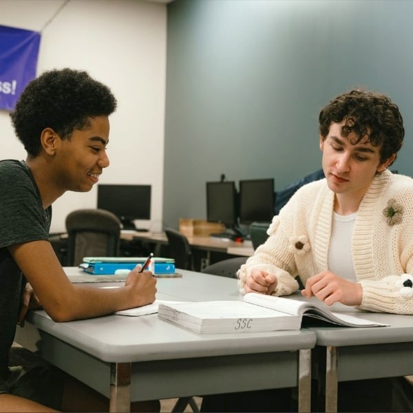 Two students peering over a textbook