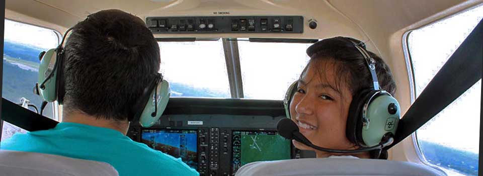 People in the front seat of a small airplane, taken from the back seat