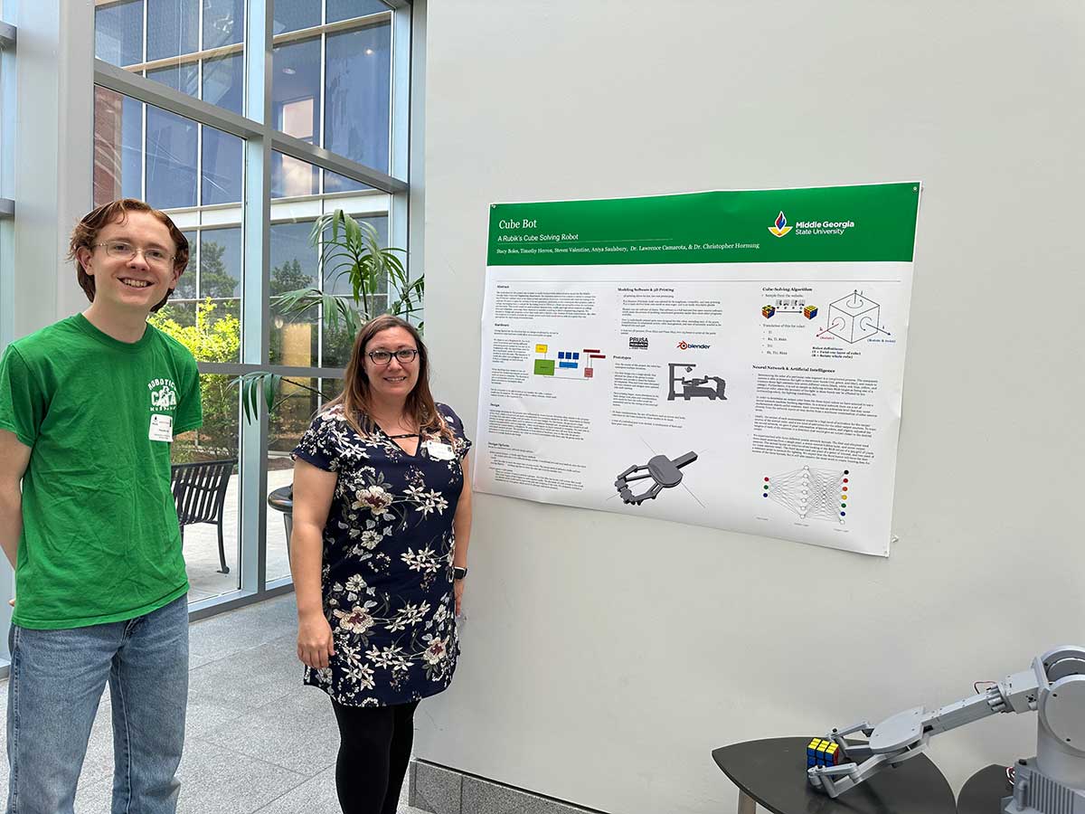 Two students giving a poster presentation on the cube bot