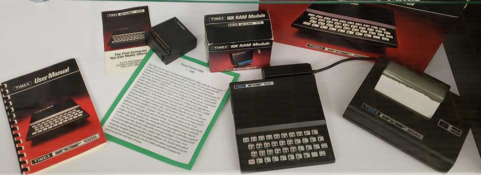 A Timex Sinclair 1000, 2040, and 16K RAM Module devices with packaging and user manual. The promotional slip reads The First Computer You Can Really Afford