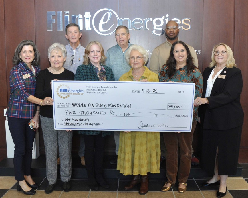 Nancy White and Karen Hix holds the scholarship check with 7 members of the Flint Energies group