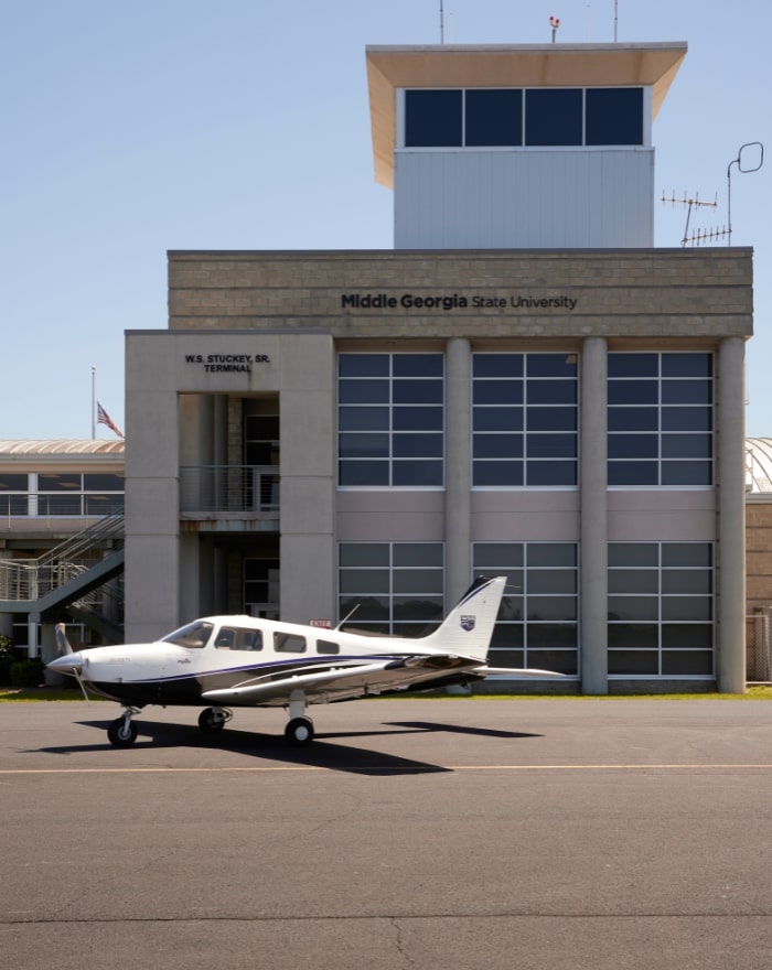 A small plane parked in front of the W.S Stuckey Sr. Terminal building at MGA's Eastman campus