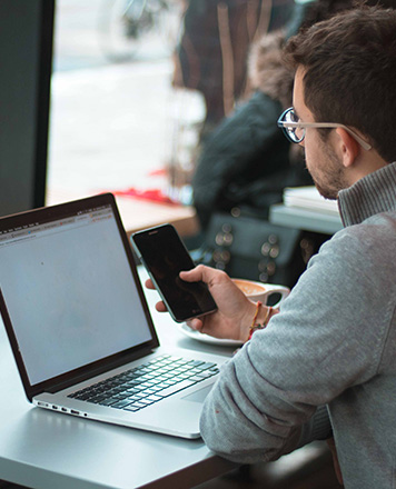 A student using a phone and a laptop.