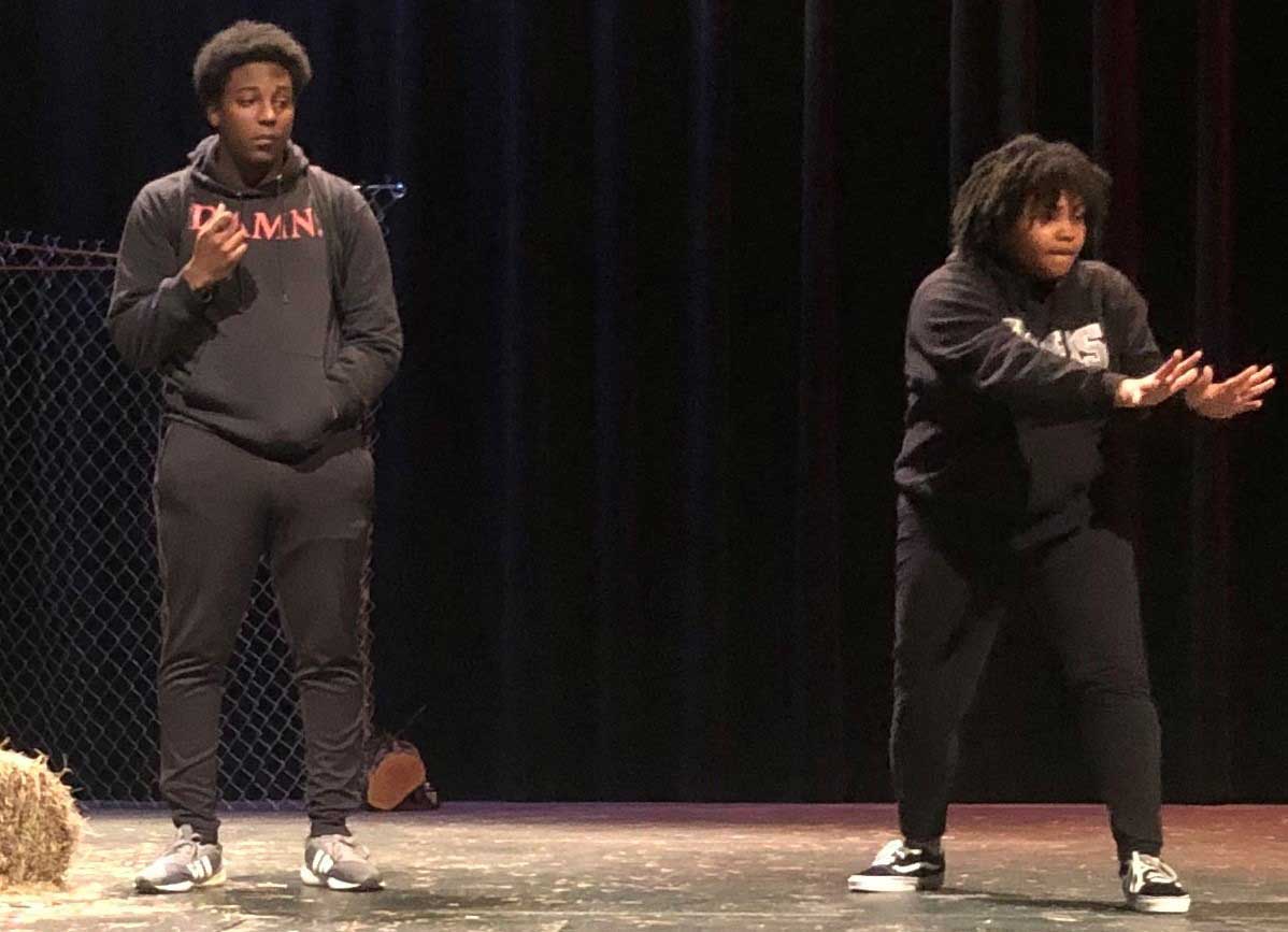 A pair of students acting while dressed in black