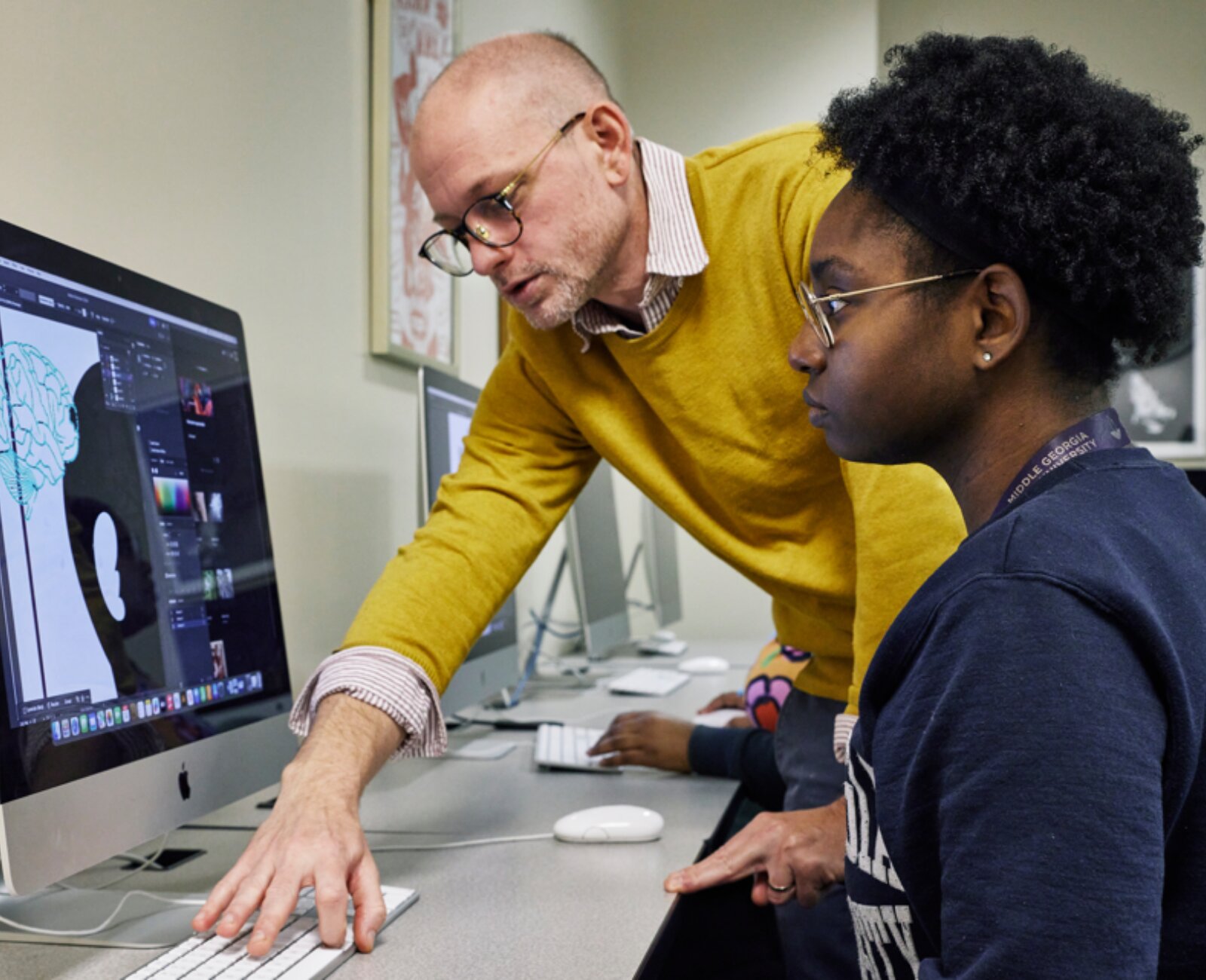 student designing while a professor supervises