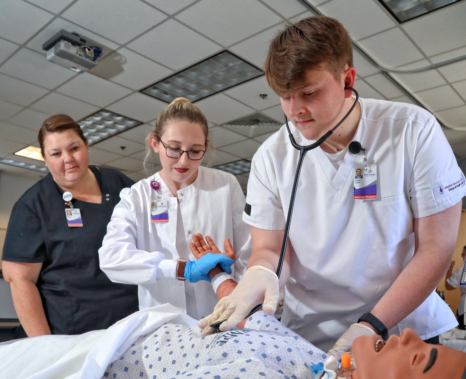 nursing students in uniform practicing on a simulation manikin