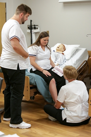 a teacher instructing nursing students beside a hospital bed