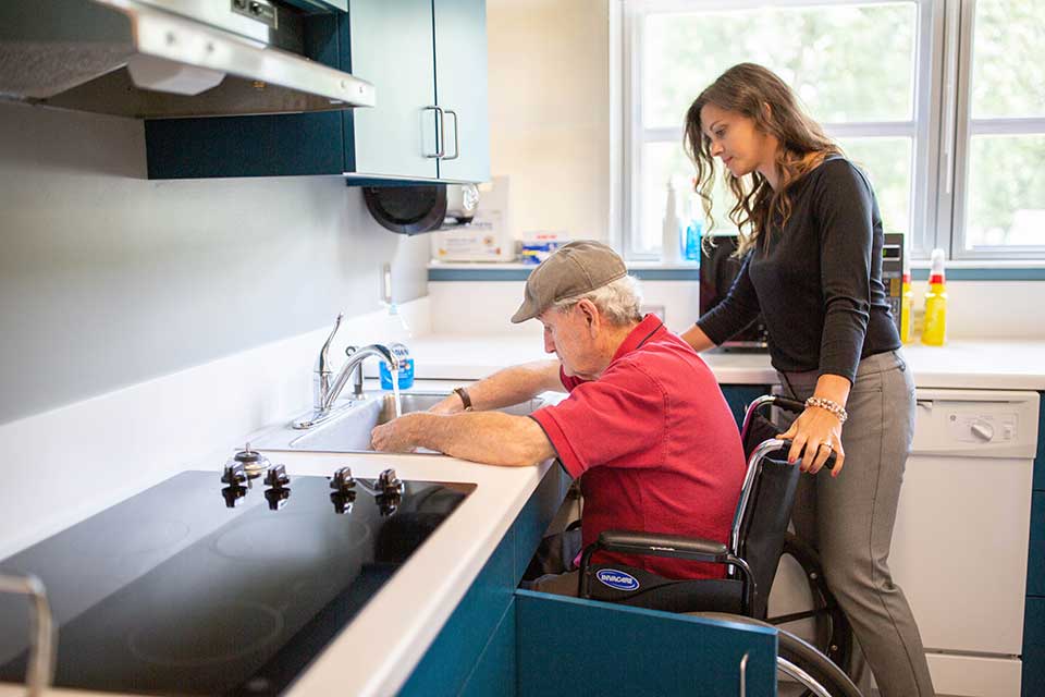 a man in a wheel chair being assisted at a sink by a woman.
