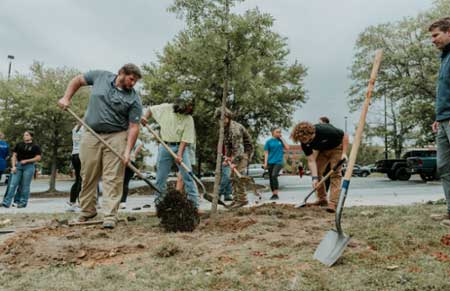 Tyler Austin, MGA grounds manager, assists FFA student volunteers at the 2023 Arbor Day Celebration and Tree Planting Ceremony. 