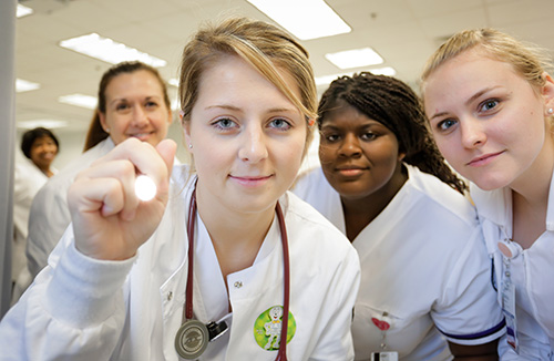 a nursing student holding a flashlight at the camera