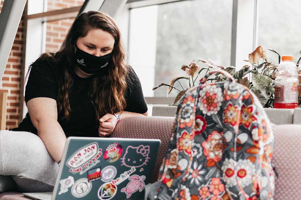 student sitting on a couch using a laptop