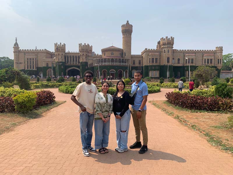 Four students in front of the Bengaluru Palace