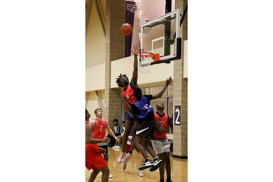 students playing basketball, blocking a shot