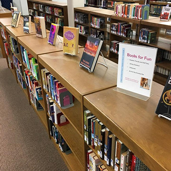 Photo of a library rooms with multiple shelves of books and books on display