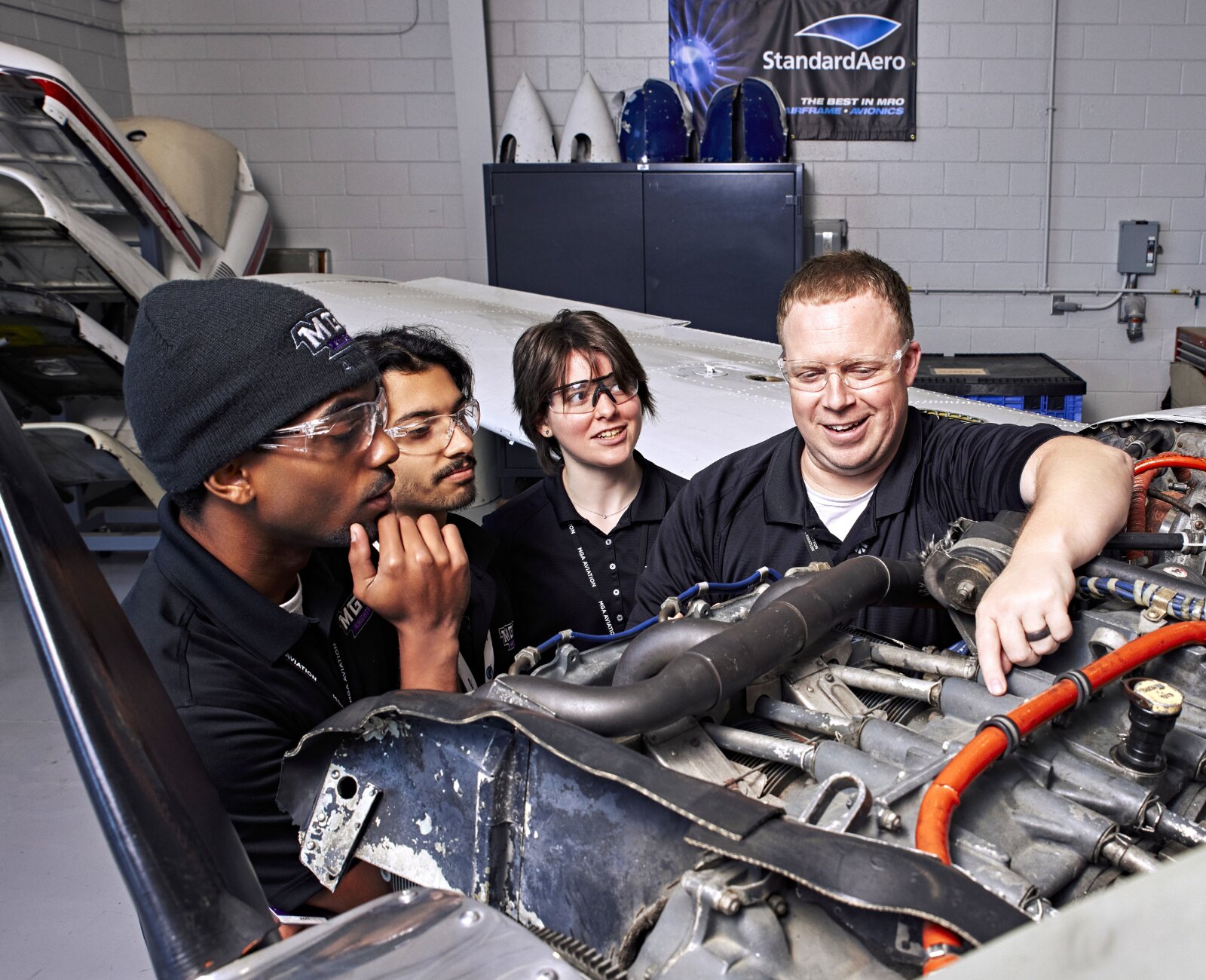 students watching an aviation professor demonstrate maintenance on a piper aircraft