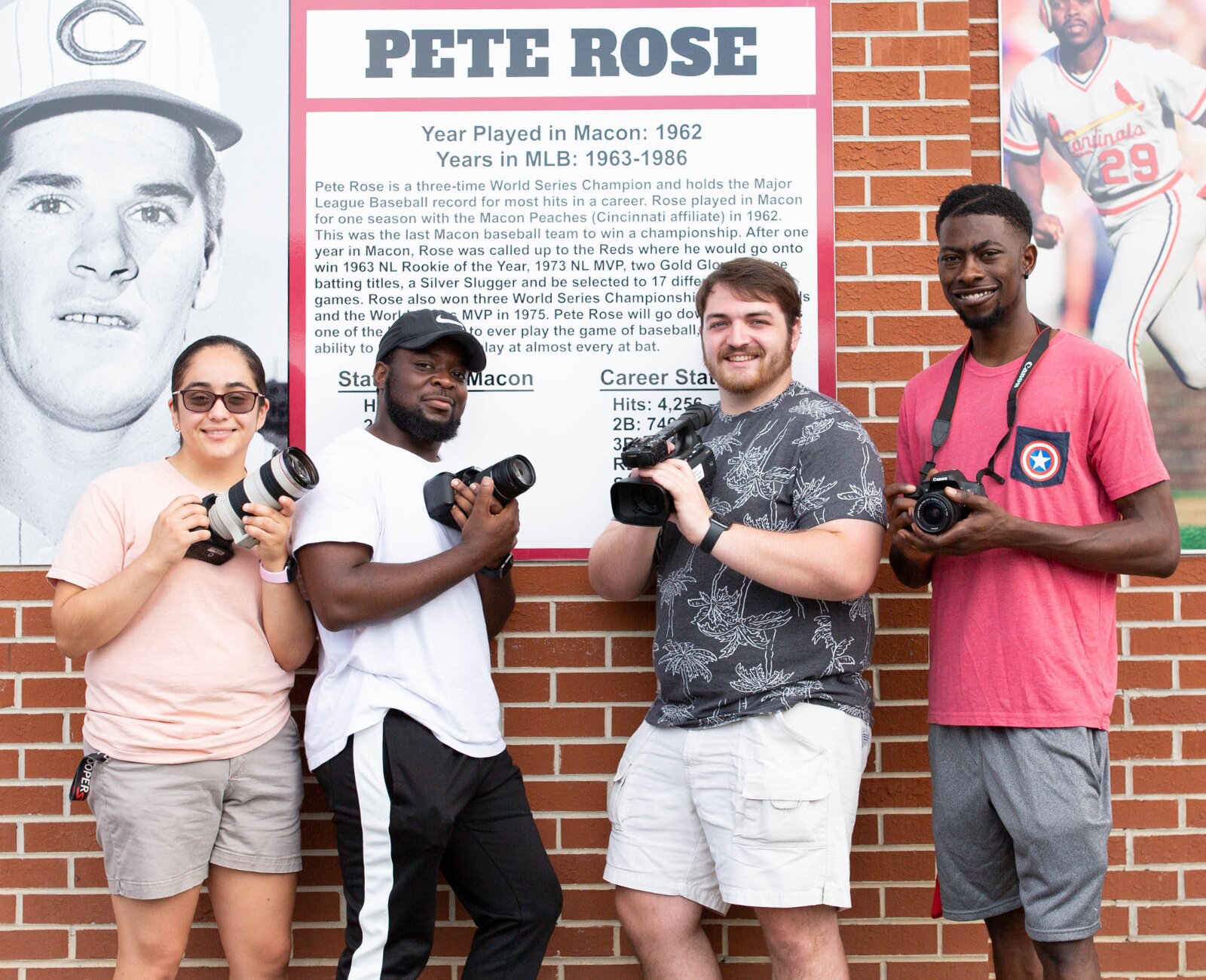 four sports management students at the Macon Bacon field with their photography equipment