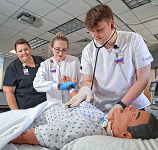 Nursing students looking at an illustration of a human spine.