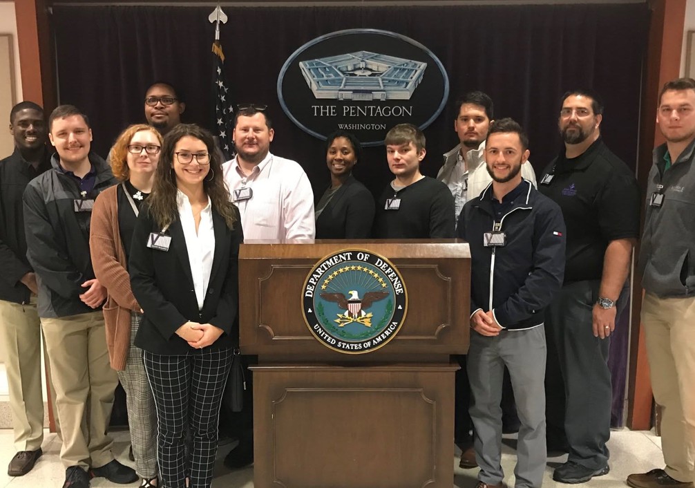 Group of MGA students standing by the Department of Defense podium in the Pentagon